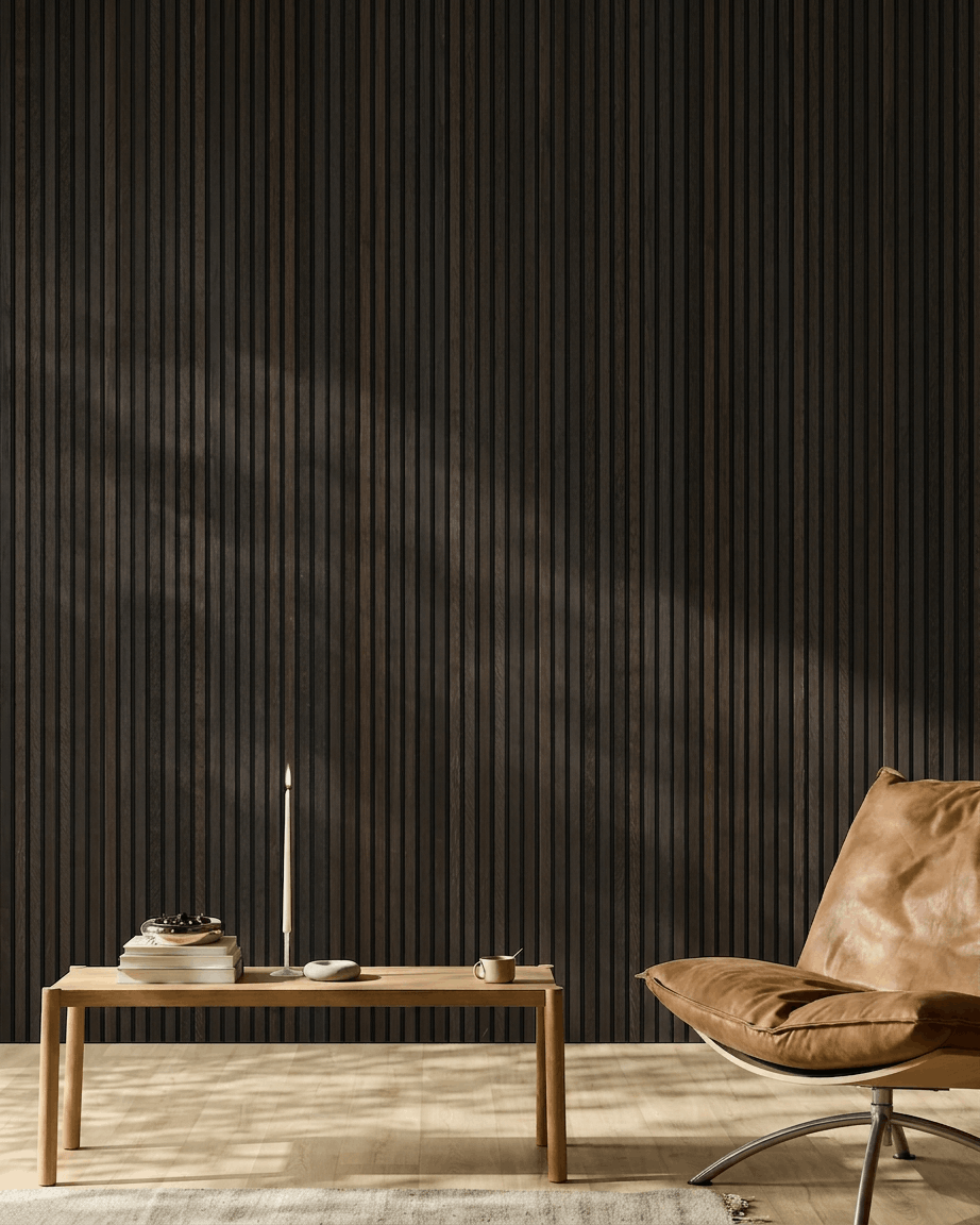 Minimalistiskt rum med en brown läderfåtölj, soffbord och inredningsdetaljer framför en vägg med WoodUpp Akupanel Rustic Smoked Oak akustikpanel i trä.