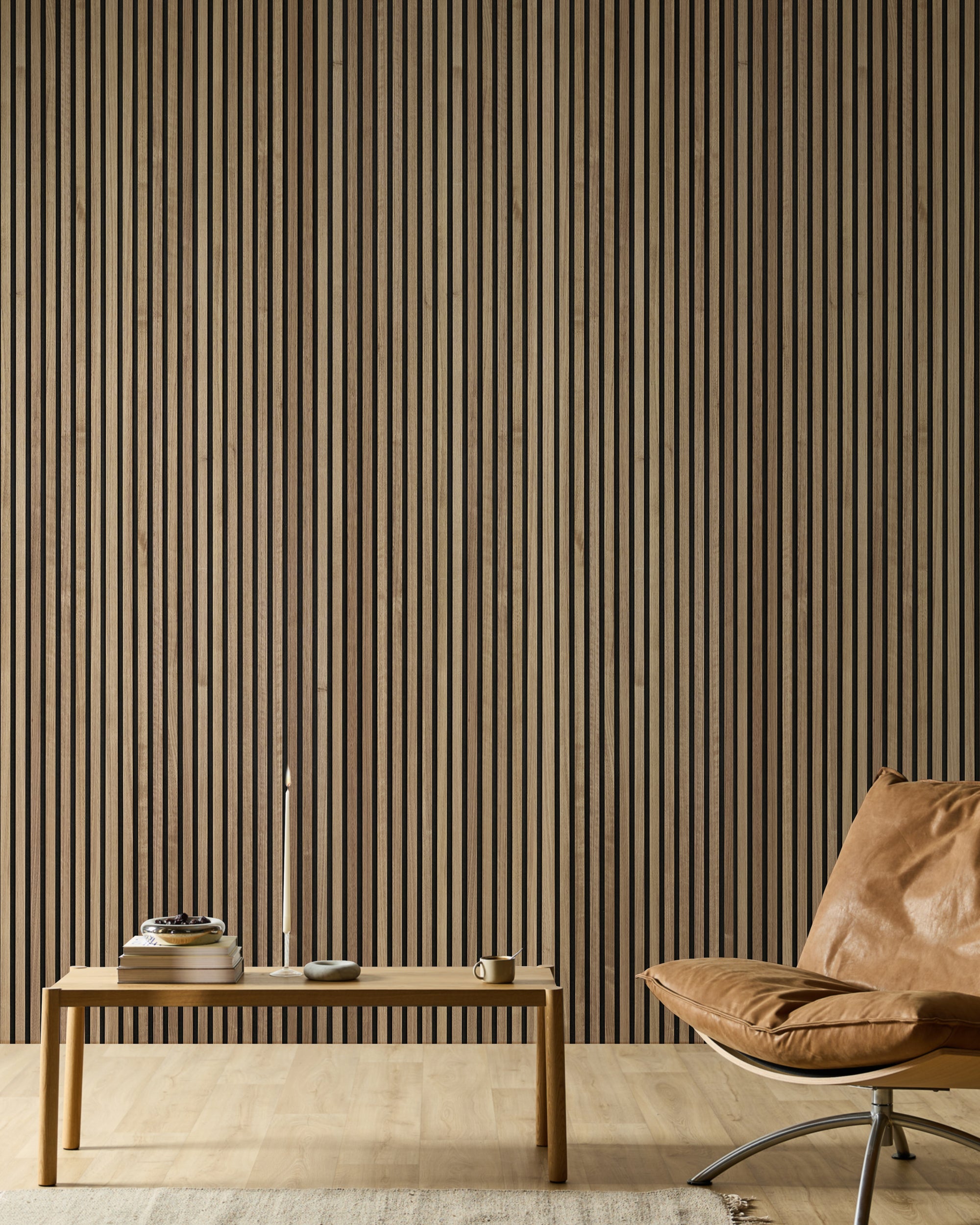 Minimalistiskt rum med en läderfåtölj, en träbänk, böcker, ett ljus och en modern Akupanel accentvägg i trä med akustiska lameller i neutrala toner.