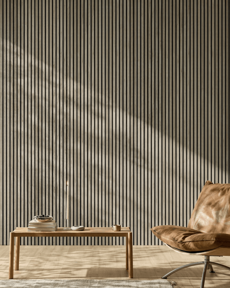 Minimalistiskt rum med en 240x60 cm WoodUpp Akupanel i Weathered Oak med black filt, träbänk, böcker, ljus, kopp och en ljusbrun läderfåtölj.