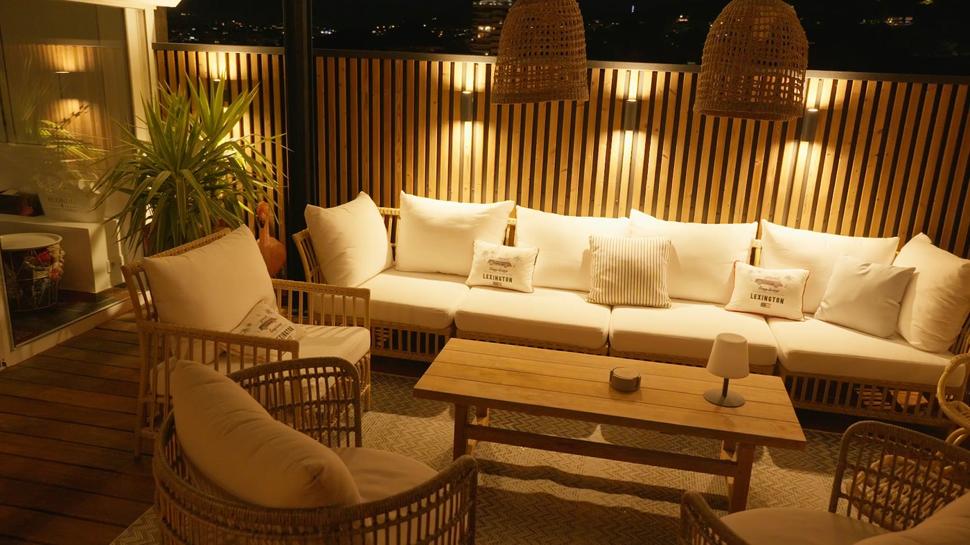 Akupanel wood slat acoustic wall panels on balcony with wicker seating and warm wall lights
