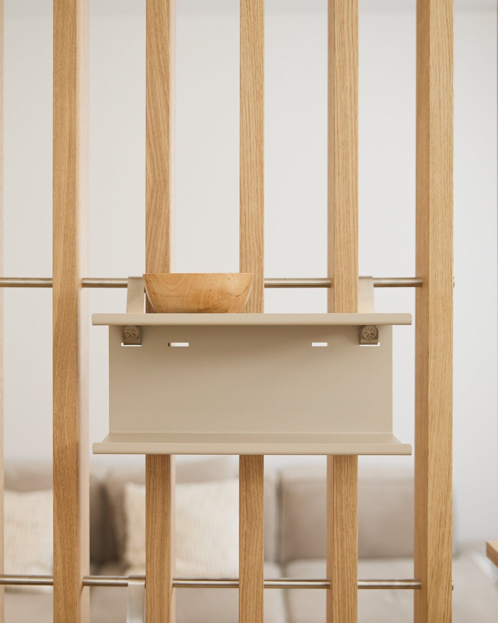 En small träskål på beige Nell Double Metal Shelf från WoodUpp (31,7 cm), med en suddig soffa och kuddar i bakgrunden.