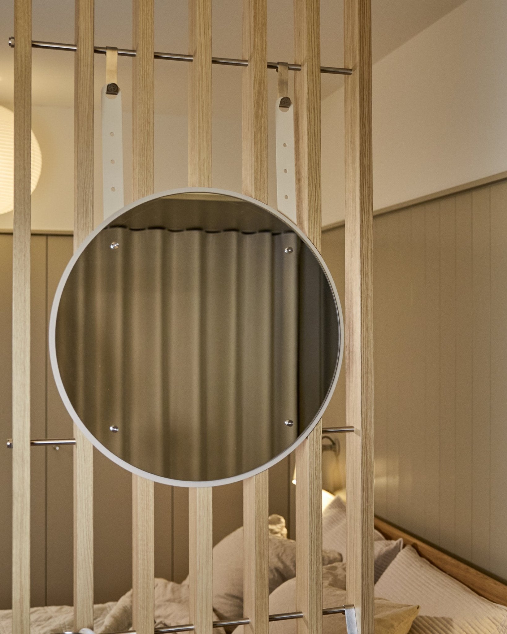 Rund, höjdjusterbar Vala BM1 spegel från WoodUpp, 54 cm i diameter, monterad på vertical akustisk träspaltpanel i mjukt neutralt ljus.