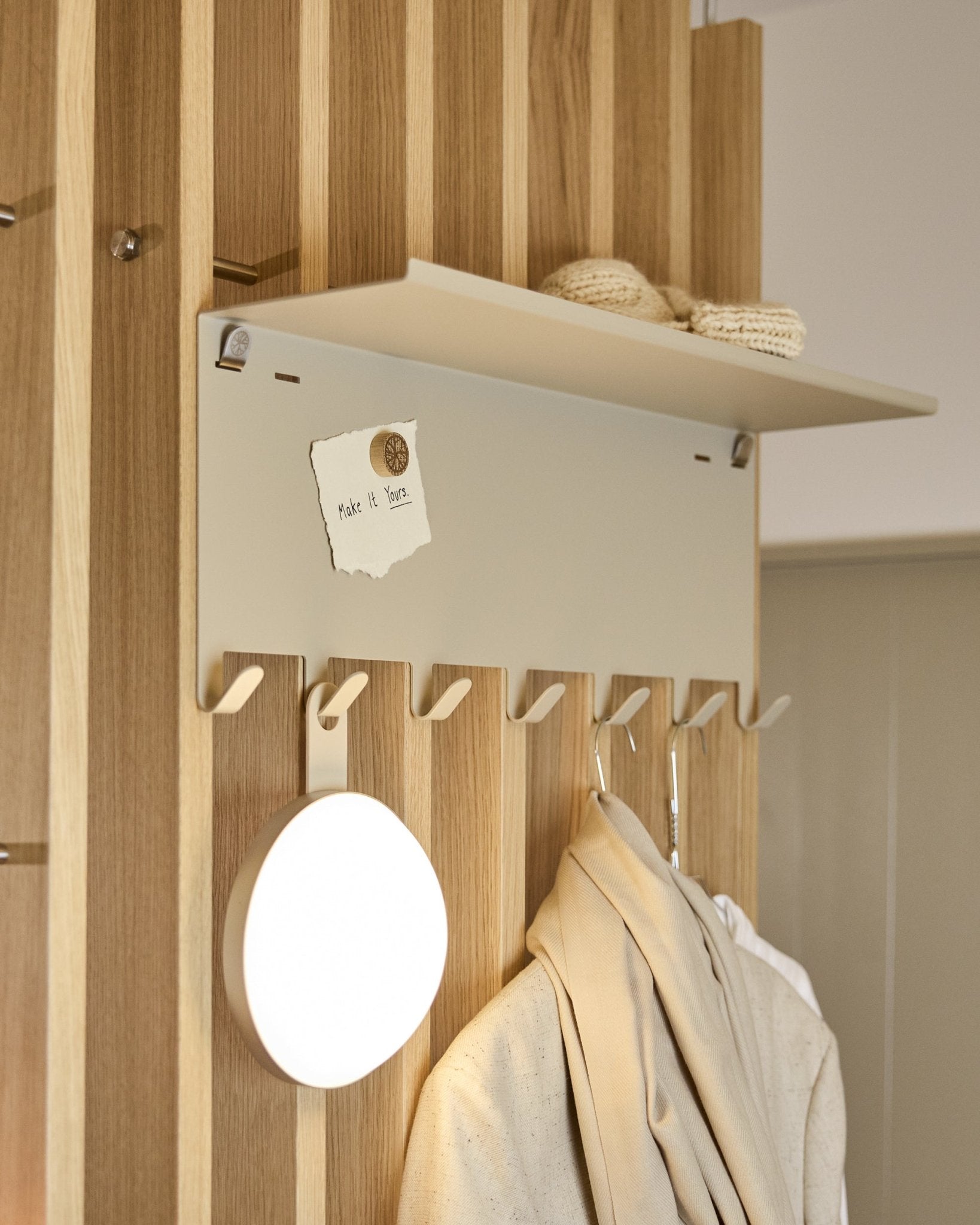 WoodUpp Nell | klädhängare BM1 i beige (63,5 x 24 cm), med steel krokar och en hylla med stickat och en lapp där det står embrace BM1.