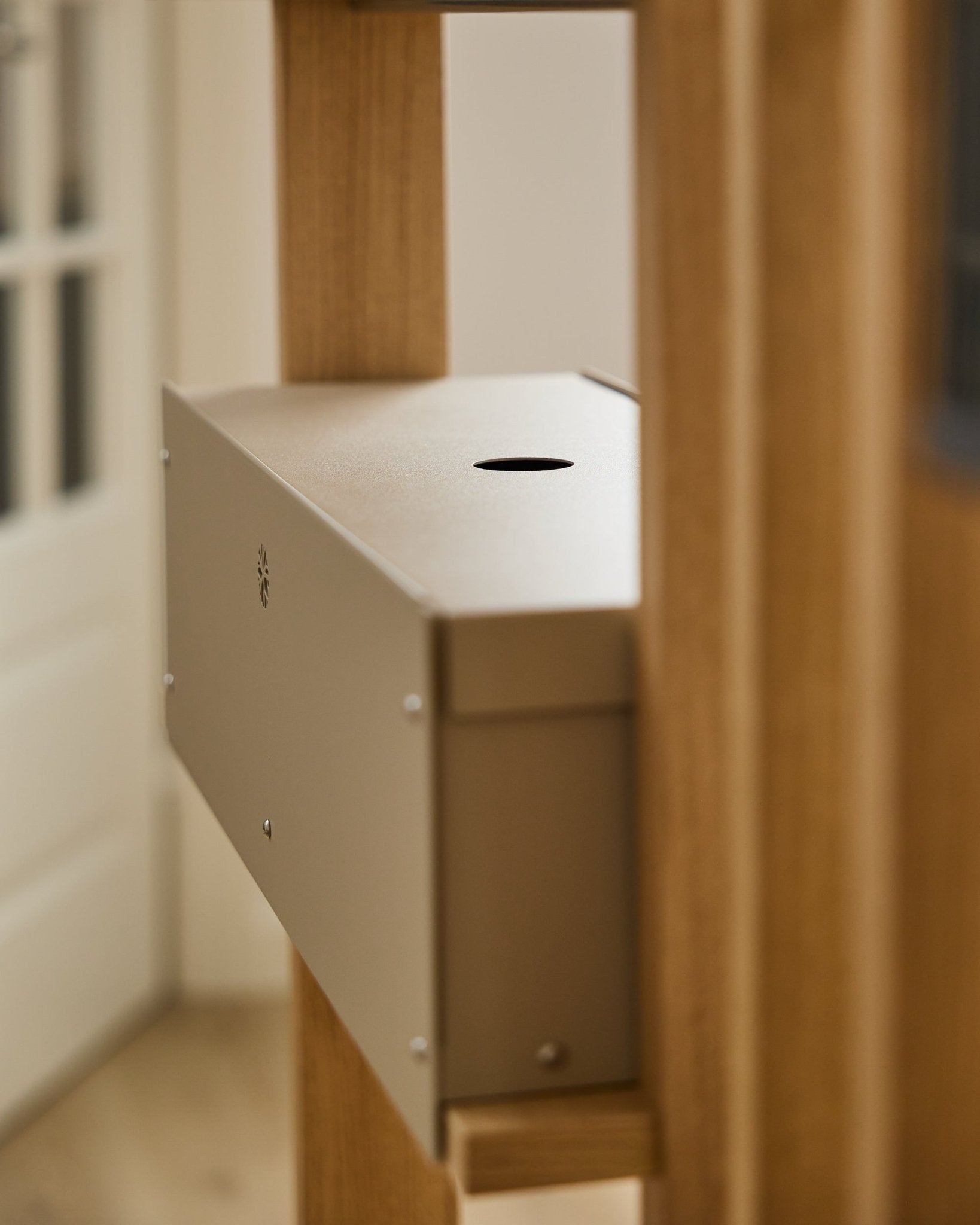 Nell | Metal Box / BM2, Beige från WoodUpp är ett pulverlackerat tillbehör i steel från CREATE-kollektionen, placerat mellan akustiska träpaneler intill en vit dörr.