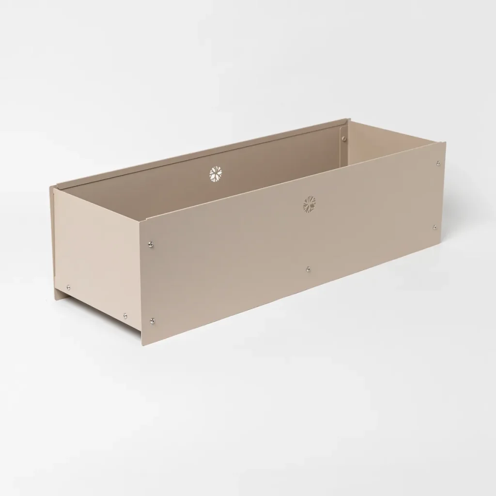 WoodUpp rektangulär planteringslåda i beige pulverlackerad metall, lång och låg. Produkten visar raka panelsidor fästa med synliga skruvar, små dekorativa genombrutna blommönster för dränering och luftning samt enkel modulär konstruktion för odling på balkong eller uteplats. Väderbeständig och hållbar design.